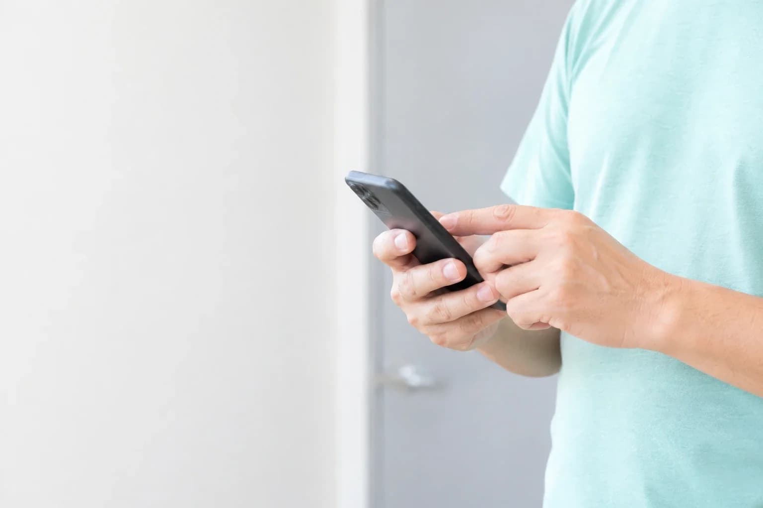 ドアの前でスマートフォンを操作する手元
